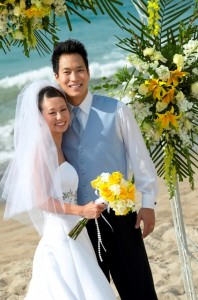 Newlywed Couple Stand on a Beach Under a Pergola